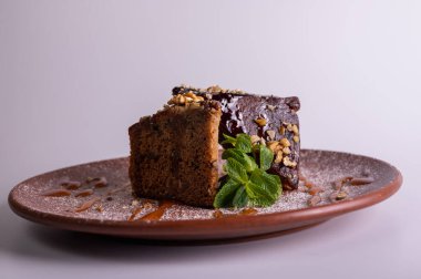 Çikolata jöleli ve kil tabakta naneli fındıklı kek dilimi. Ev yapımı ballı tatlı, ceviz ve karamel şurubu. Gurme tatlı pasta konsepti