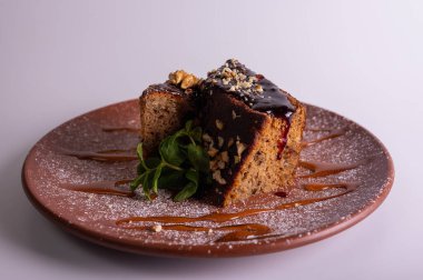 Çikolata jöleli ve kil tabakta naneli fındıklı kek dilimi. Ev yapımı ballı tatlı, ceviz ve karamel şurubu. Gurme tatlı pasta konsepti