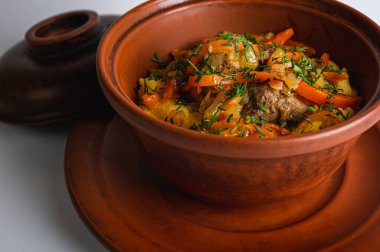 Etli, patatesli ve havuçlu geleneksel güveç. Orijinal Doğu Avrupa mutfağı tarafsız bir arkaplanda seramik sofra takımında servis edilir. Makro yemek atışı.