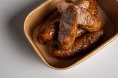 El yapımı karton kutuda nefis ızgara domuz sosisi. Sulu dilimlenmiş sosisli sandviçin üst görüntüsü. Barbekü, yemek ve yemek servisi için meze.