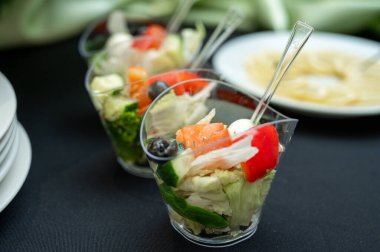 Taze Yunan salatası aperatifleri mini çatallı plastik bardaklarda. Sağlıklı Akdeniz sebze atıştırmalıkları catering etkinlikleri, açık büfe servisi veya düğün partisi için