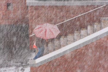 Bulanık bir görüntü - kırmızı bir şemsiyenin altına tırmanan biri görüntüyü bulanıklaştırıyor - kar altında kırmızı bir şemsiye altında yürüyen bir adam