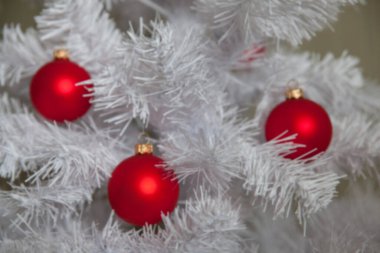 blurred image - red Christmas balls on a white fir-tree