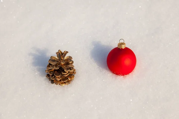 クリスマスツリーのおもちゃの赤いボールと白い雪の上に装飾的な松のコーン — ストック写真