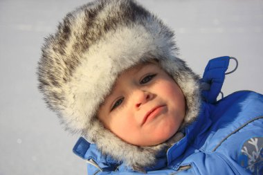 Kışlık giysiler içinde mutlu küçük bir çocuğun yakın plan portresi.