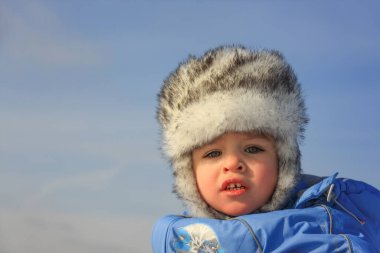 Kışlık giysiler içinde mutlu küçük bir çocuğun yakın plan portresi.