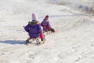 Çocuklar kışın dağdan kayarak geliyorlar.