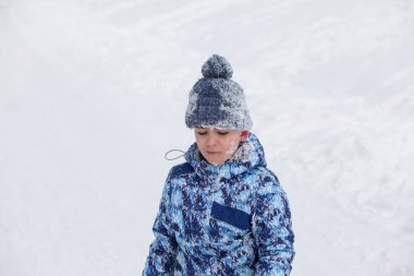 Küçük çocuk karda oturuyor.