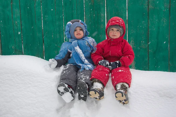 Due Ragazzini Abiti Invernali Sono Seduti Sulla Neve Sullo Sfondo — Foto Stock