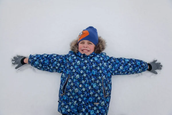 Ευτυχισμένο Αγοράκι Χειμωνιάτικα Ρούχα Ξαπλωμένο Στο Χιόνι — Φωτογραφία Αρχείου