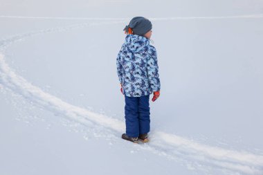 Küçük çocuk taze karda oynuyor.
