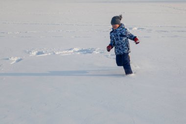 Küçük çocuk taze karda oynuyor.