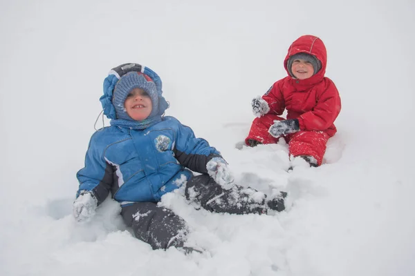 冬の服を着た2人の少年が雪の中で — ストック写真