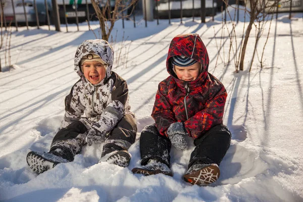 Δύο Χαρούμενα Αγοράκια Χειμωνιάτικα Ρούχα Που Κάθονται Στο Λευκό Χιόνι — Φωτογραφία Αρχείου