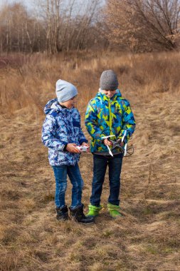 Erkekler, insansız hava aracını bir bahar manzarasının arka planında kontrol ediyorlar. İHA uçuyor