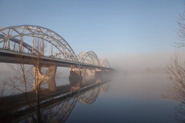 Büyük bir nehrin üzerinde bir köprü ilkbaharın başlarında nehirde sis.