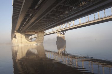 Büyük bir nehrin üzerinde bir köprü ilkbaharın başlarında nehirde sis.