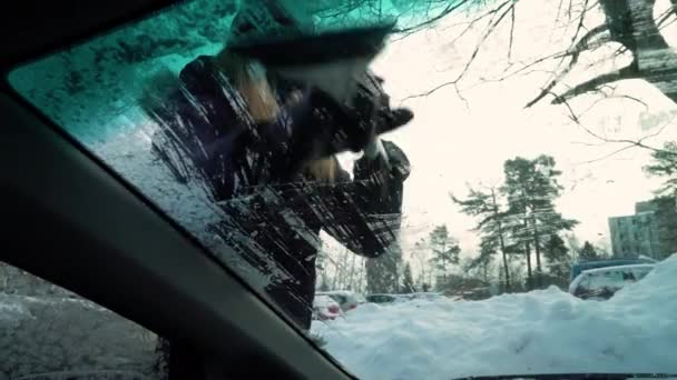Mladá žena se sněhem kartáč škrábání led z čelního skla auta — Stock video