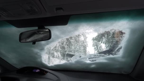 Молода жінка зі сніжною щіткою очищає лід від лобового скла автомобіля — стокове відео
