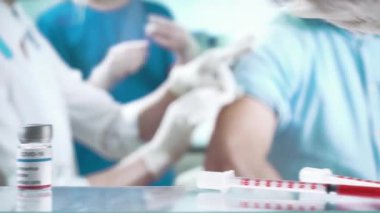Bir hemşire klinikteki bir hastaya aşı enjekte ediyor..