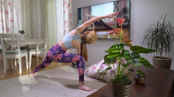 Nő követően jóga online video tutorial a nappalijában — Stock videók