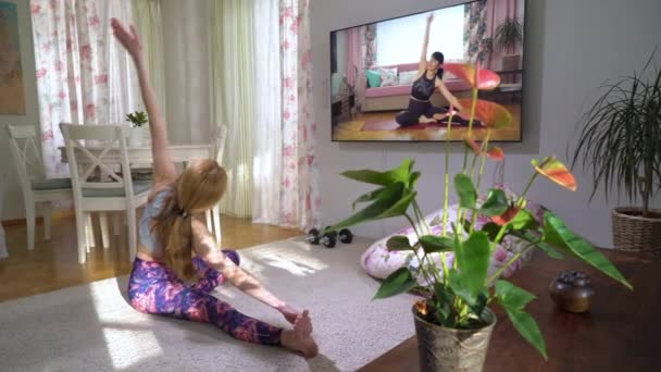 Mujer siguiendo yoga video tutorial en línea en su sala de estar — Vídeos de Stock