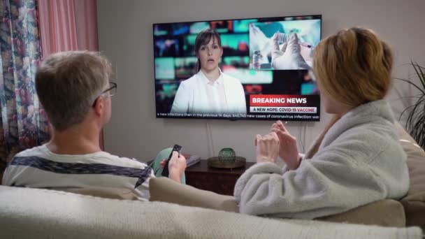 Família casal assistindo TV notícias sentado no sofá na sala de estar juntos. — Vídeo de Stock