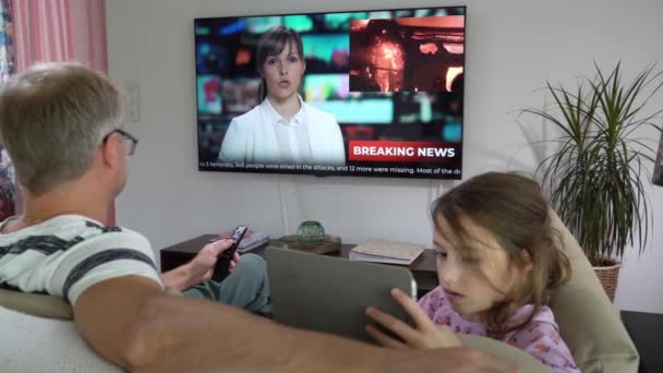 Een man van middelbare leeftijd met zijn dochtertje voor een tv-scherm. — Stockvideo