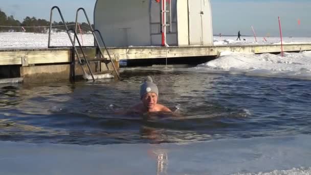冬に氷の穴を泳いでいる男. — ストック動画
