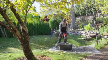 Güneşli bir sonbahar gününde Finlandiya 'nın kırsal kesimlerinde betonu karıştıran adam. Otantik yaşam tarzı ve sıcak ışık, kırsal atmosfer ve verimli ruh hali ile el emeği kavramı.
