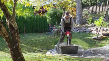 Güneşli bir sonbahar gününde Finlandiya 'nın kırsal kesimlerinde betonu karıştıran adam. Otantik yaşam tarzı ve sıcak ışık, kırsal atmosfer ve verimli ruh hali ile el emeği kavramı.