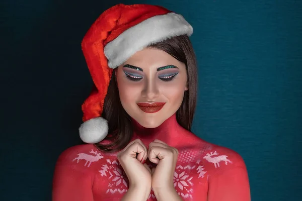 Une jeune femme brune avec un maquillage d'art idéal et un chapeau de Père Noël fait un vœu les yeux fermés — Photo