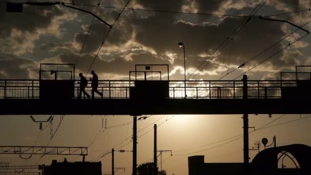 Silhouetten von Menschen, die die Eisenbahn auf einer alten Metallbrücke überqueren — Stockvideo