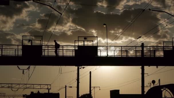 Silhouetten von Menschen, die die Eisenbahn auf einer alten Metallbrücke überqueren — Stockvideo