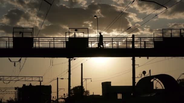 Silhouetten von Menschen, die die Eisenbahn auf einer alten Metallbrücke überqueren — Stockvideo