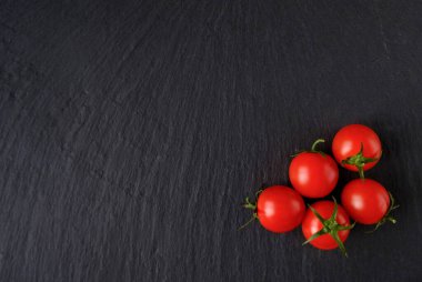 Koyu taşlı arka planda taze kırmızı domatesler. Üst Manzara. Boşluğu kopyala 