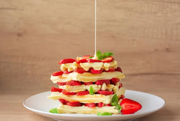 Taze çilekli Belçika waffle 'ları ve beyaz tabakta nane şekeri. Ahşap arkaplan