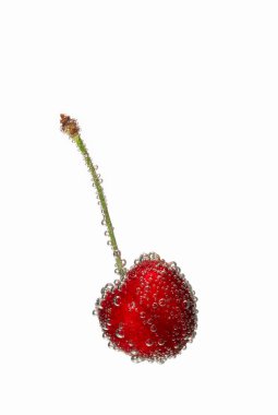 Beyaz arka planda kabarcıklar olan suda kiraz.