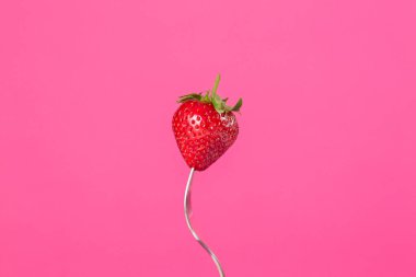 Pembe arka planda çatallı taze çilekler