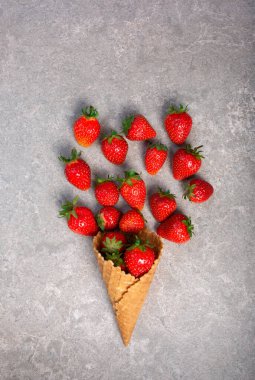 Gri taşlı arka planda waffle kabında taze çilekler.