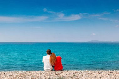 Bir çift deniz kenarında oturuyor.