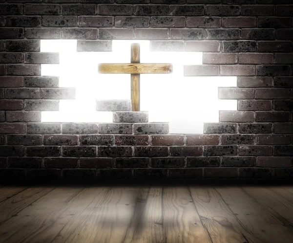 Houten kruis achter een gebroken bakstenen muur met wit licht in de achtergrond. — Stockfoto