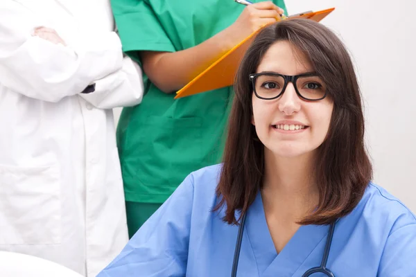 Läkare leende i förgrunden — Stockfoto