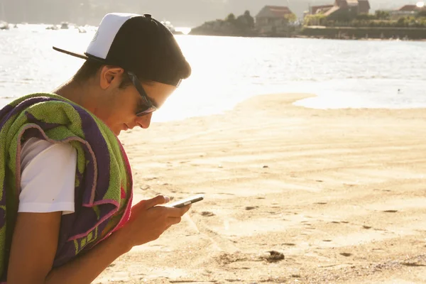 Mladík na pláži se mobile — Stock fotografie