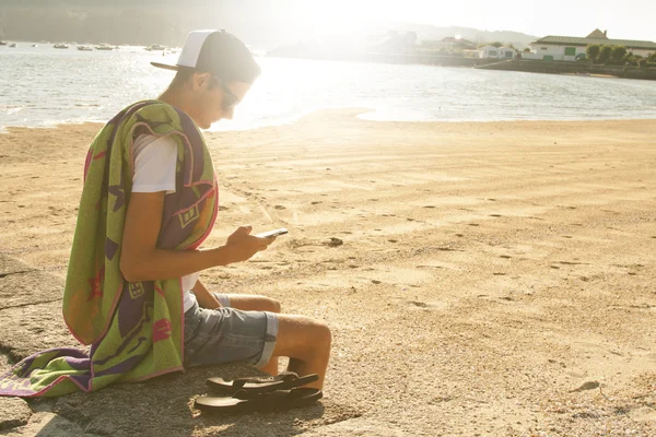 Giovane ragazzo sulla spiaggia con cellulare — Foto Stock