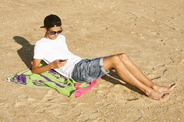 Νεαρό αγόρι στην παραλία με το κινητό — Φωτογραφία Αρχείου