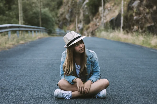Девушка, сидящая на дороге — стоковое фото