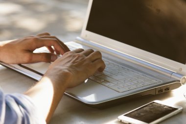 Eller dizüstü bilgisayarda yazıyor. 