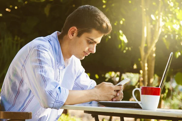 Hombre con teléfono móvil y computadora — Foto de Stock