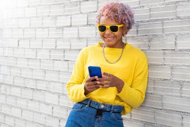 Sokakta güneş gözlüklü ve cep telefonlu sıradan bir Afro-Amerikalı kız.